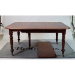 A Victorian mahogany extending dining table with two extra leaves on turned supports,