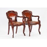 A pair of Victorian mahogany framed brown leather upholstered open armchairs, with serpentine...