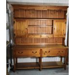 A modern pine kitchen dresser with plate rack flanked by cupboard doors over two short drawers