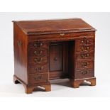 A mid-18th century Irish mahogany estate desk with lift slope top over brushing slide and ten...