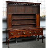 An inlaid George III oak dresser, the enclosed three tier plate rack with flanking cupboards,...