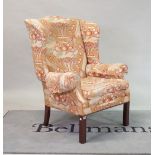 An 18th century style wingback easy armchair, on block supports