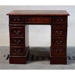 A modern stained beech kneehole pedestal desk with an inset leather top