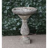 A modern reconstituted stone circular birdbath