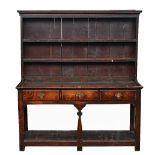 A George III oak dresser, the enclosed two tier plate rack over three frieze drawers, united...