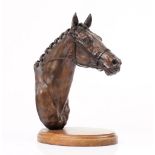 A bronzed model of a horse head mounted on an oval wooden plinth