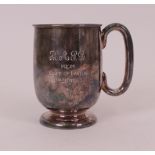 A silver mug, with a 'C' shaped handle, raised on a circular foot, the body presentation...