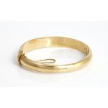 A gold oval hinged bangle, on a snap clasp, fitted with a safety chain, gross weight 18 gms.