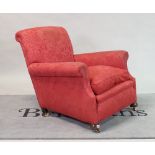 An early 20th century red upholstered easy armchair on bun feet