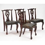 A set of four George III style carved mahogany pierced splat back dining chairs on claw and...