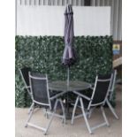 A modern grey painted metal and glass circular garden table with associated umbrella,