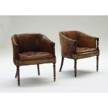 A pair of Regency style brown leather upholstered mahogany framed tub back chairs