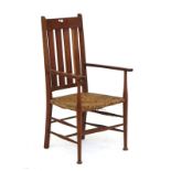 An Arts & Crafts teak framed rush seat open armchair