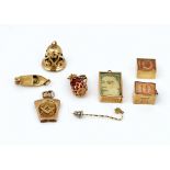 Seven mostly gold pendants and charms and a stick pin (8)