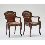 A pair of Victorian mahogany framed brown leather upholstered open armchairs