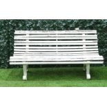 A white painted wrought iron and slatted wood garden bench