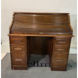 An early 20th century oak roll top desk