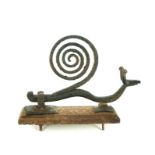 A novelty wrought iron door knocker in the form of a snail, on oak backing plate
