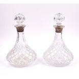 A PAIR OF SILVER MOUNTED FACETED GLASS DECANTERS AND STOPPERS (2)