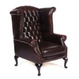 A GEORGE II STYLE BROWN LEATHER UPHOLSTERED WINGBACK ARMCHAIR