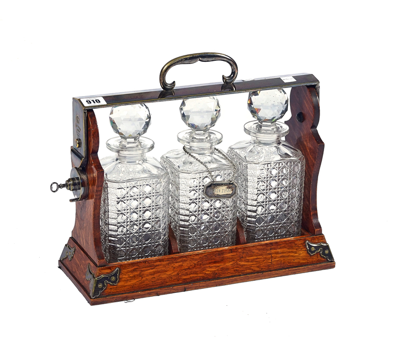 BETJEMANN’S PATENT; A LATE 19TH CENTURY SILVER PLATE AND OAK THREE BOTTLE TANTALUS