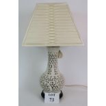 A 20th Century reticulated Blanc De Chine table lamp with lotus and cherry blossom design on a