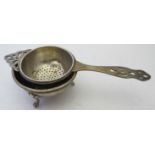A matched silver tea strainer and stand,