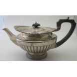 A heavy silver teapot with half fluting