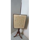 An Edwardian tapestry pole screen surmounted by a brass finial, raised on a turned pedestal,