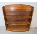 An Art Deco honey oak bow fronted open waterfall bookcase, comprising four graduated shelves.