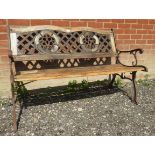 A period style teak garden bench with cast scrolled end sections and pierced latticework back,