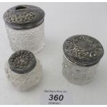 Three cut glass jars with silver tops.