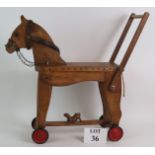 A vintage scratch built wooden child's ride on horse with metal wheels and leather bridle.