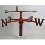 A vintage wrought iron weather vane painted red with lots of aged weather related patina.