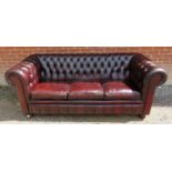 A vintage Chesterfield three seater leather sofa upholstered in a buttoned burgundy leather,