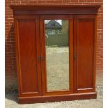 A Victorian mahogany triple wardrobe with central mirror door opening to reveal a linen press