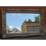 A very large reproduction bevelled rectangular wall mirror in a very ornate silver gesso frame.