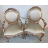 A pair of antique style French open sided giltwood framed armchairs upholstered in a grey silk