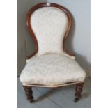 A Victorian spoon back mahogany framed nursing chair upholstered in cream patterned fabric,