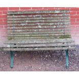 A teak garden bench nicely weathered with lichen scrolled seat raided on green painted metal strap