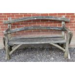 A rustic nicely weathered garden bench with slatted seat and naturalistic back rest and end
