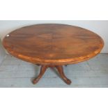 A 19th century walnut tilt top oval breakfront table with quarter veneered top featuring geometric