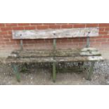 An antique garden bench of heavily weathered deep grained oak mounted on three wrought iron strap