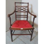 An Edwardian mahogany open sided elbow chair boxwood strung with a crimson damask seat, raised on