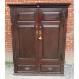 An early 18th century oak wardrobe, the double doors with brass knobs & fielded panels, opening onto