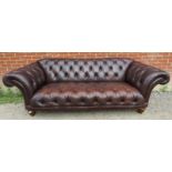 A large antique style Chesterfield sofa upholstered in distressed chocolate brown buttoned