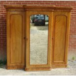 A Victorian pale mahogany breakfront triple wardrobe with central mirrored door enclosing an arrange