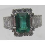 An 18ct white gold emerald & diamond cluster ring with diamond shoulders, emerald cut emerald approx