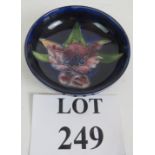 A small Moorcroft pottery dish with orchid decoration on a dark blue ground. Incised Moorcroft