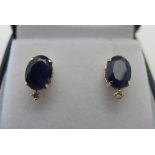 A pair of 18ct yellow gold stud earrings set with oval treated sapphire and round cut diamond,